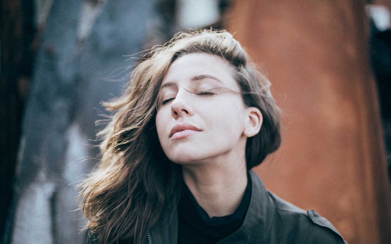 A woman with her eyes closed, practicing deep breathing meditation.