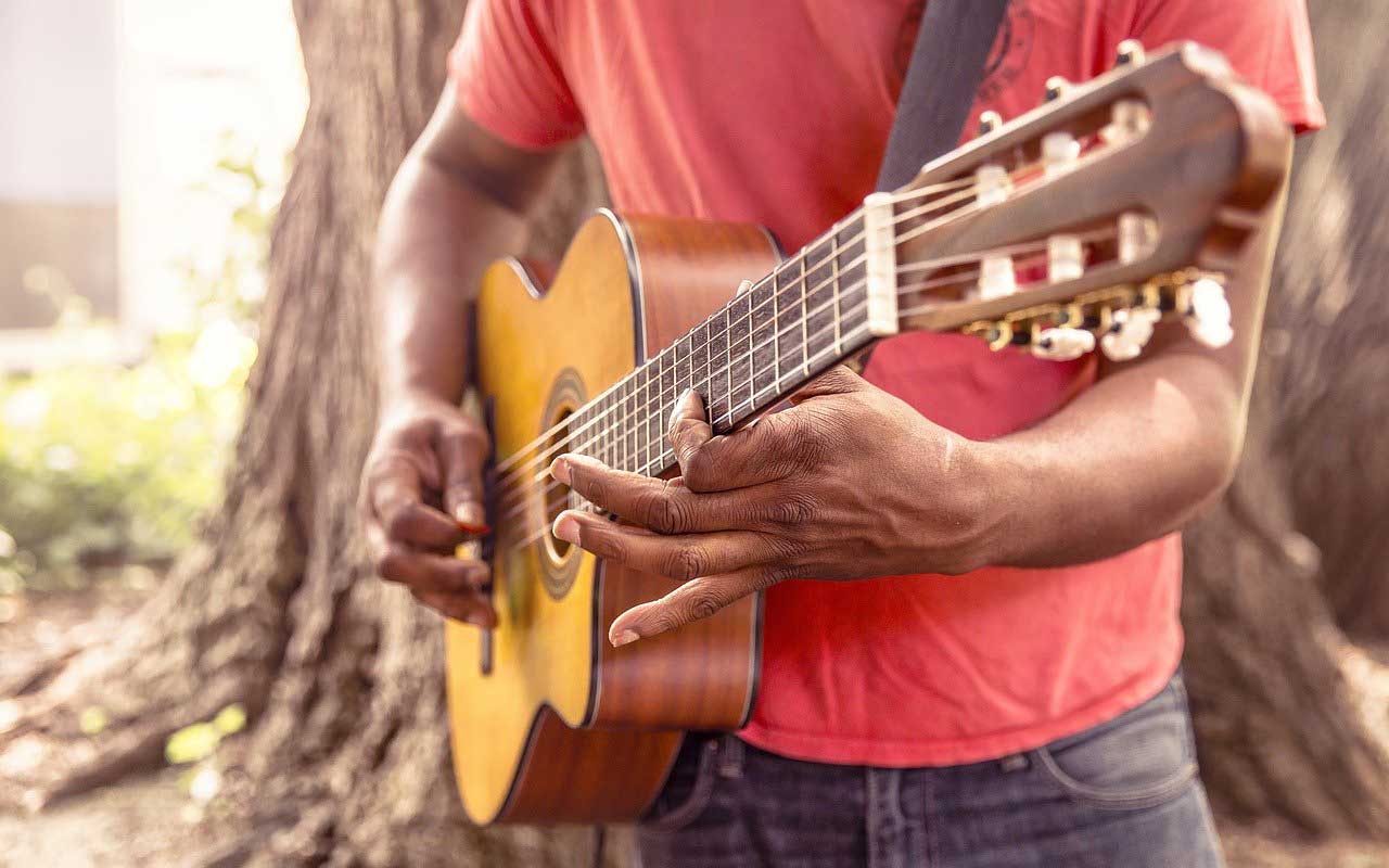 A man plays the guitar as he learns how to memorize lyrics.