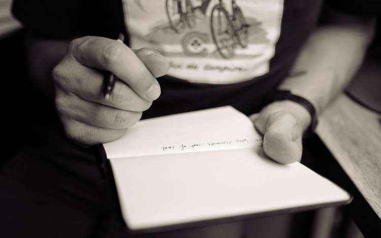 A person writing in a journal, a key to testing how to memorize song lyrics.