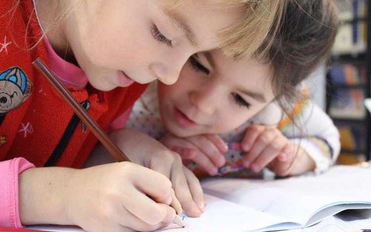 Two children focusing on a coloring book.