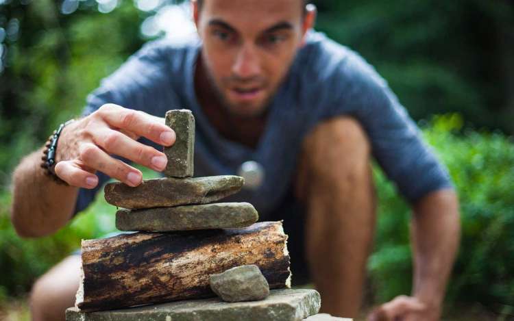 A man focused on stacking stones.