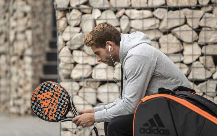 A tennis player holds his racquet, waiting for a match to start.