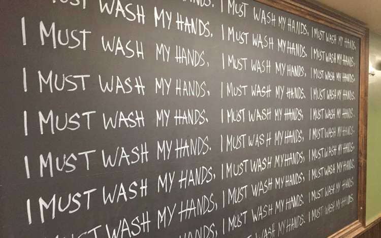 A chalkboard with "I must wash my hands" written repeatedly.