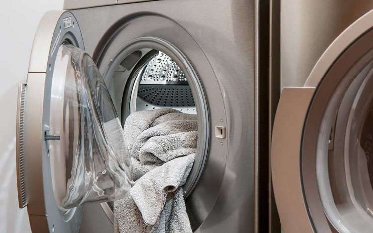 A clothes dryer with clean towels spilling out.