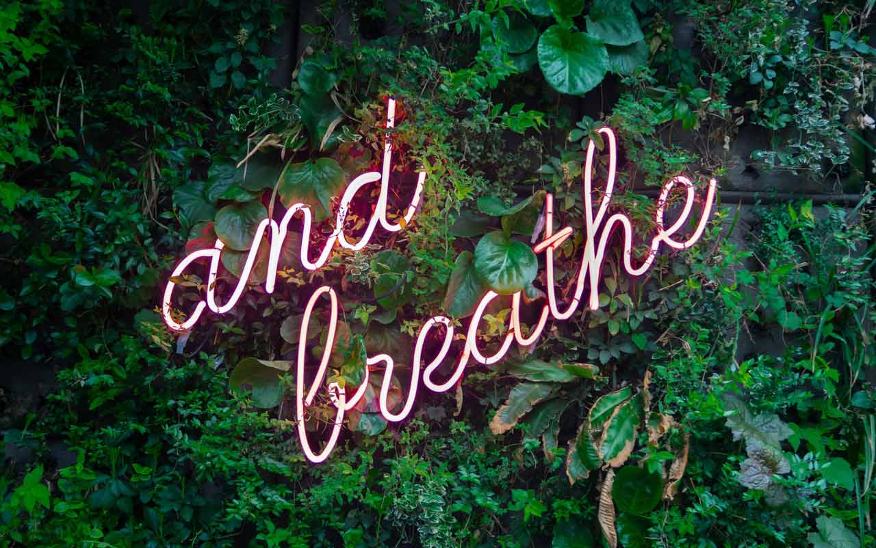 A neon sign that reads "and breathe."