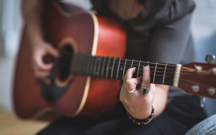 A person plays guitar, a long-term learning project that could help you work with focus.