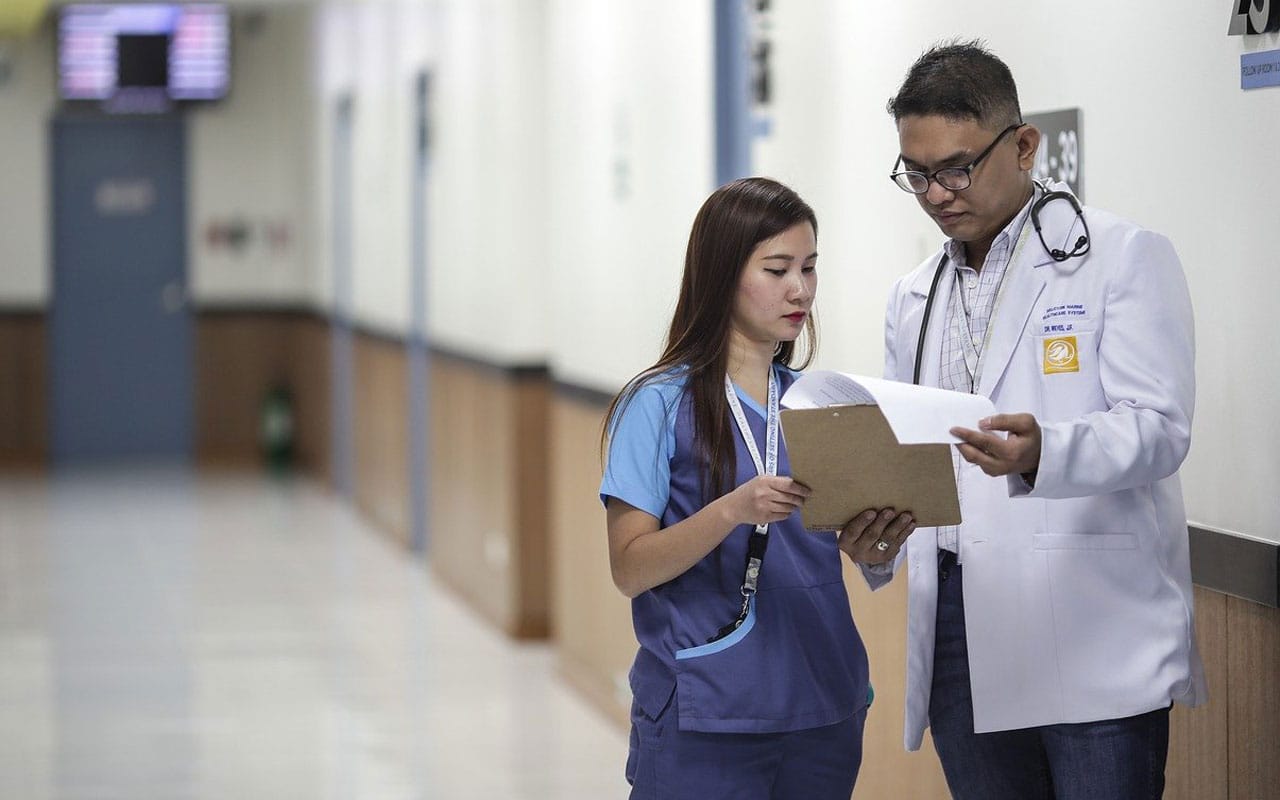 A doctor and their assistant check a patient's chart.