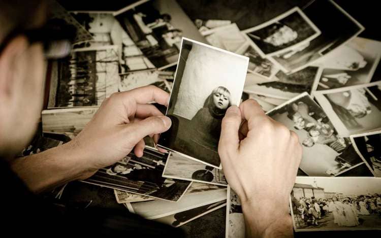 A person holds an old sepia-toned photo of a young girl. Memory loss can make it difficult to remember even close family members.