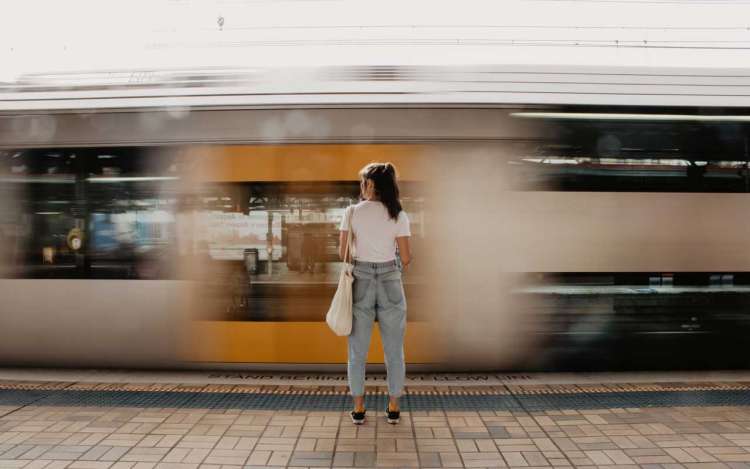 A woman watches a train speed by. 