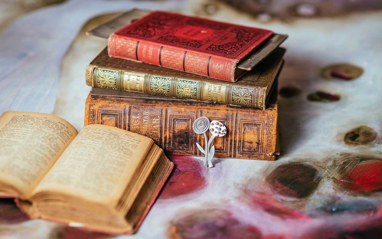 A stack of thick leather-bound books sits on a table. Long-form content helps you learn how to increase attention span.