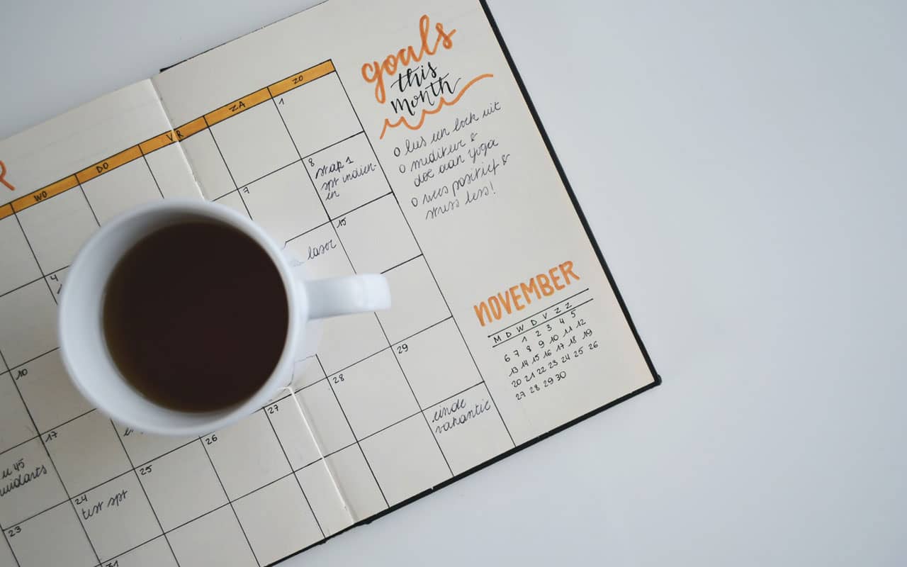 A goals calendar with a cup of coffee sitting on top.