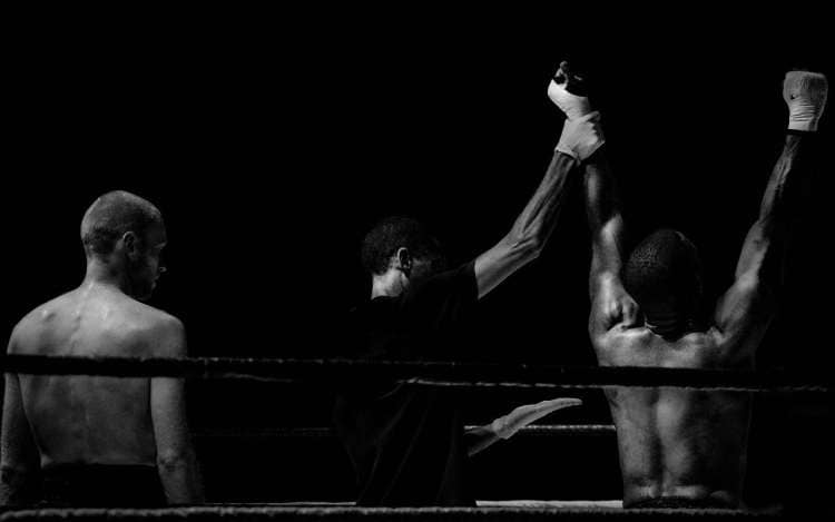 A referee holds up the arm of a victorious boxer. 