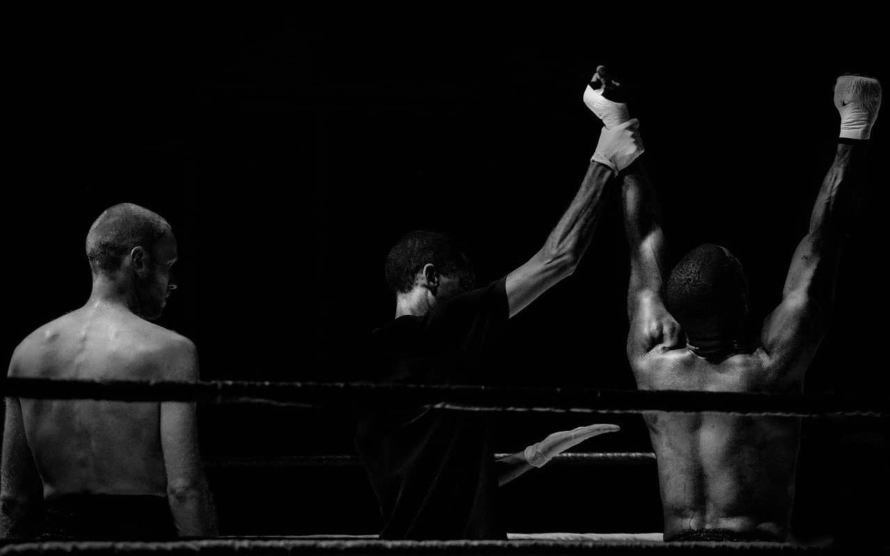 A referee holds up the arm of a victorious boxer. 