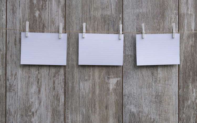 Three blank index cards hung on a piece of string with clothespins.