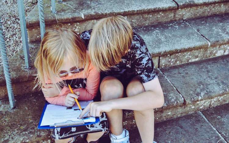 Two children study together while sitting on steps.