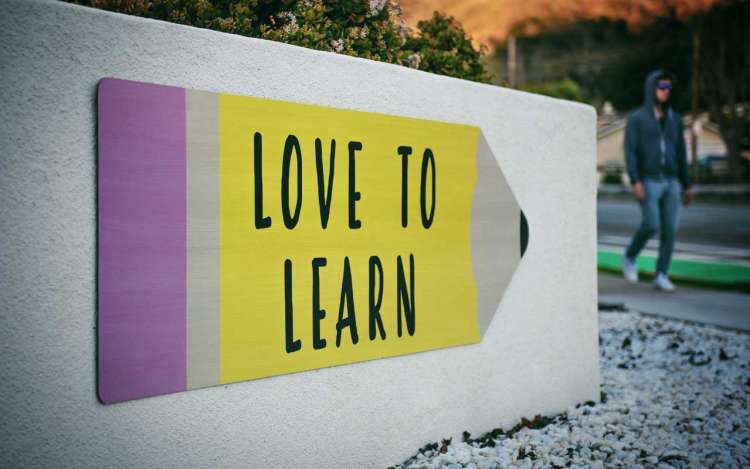 A sign reads "love to learn," drawn over a large yellow pencil.