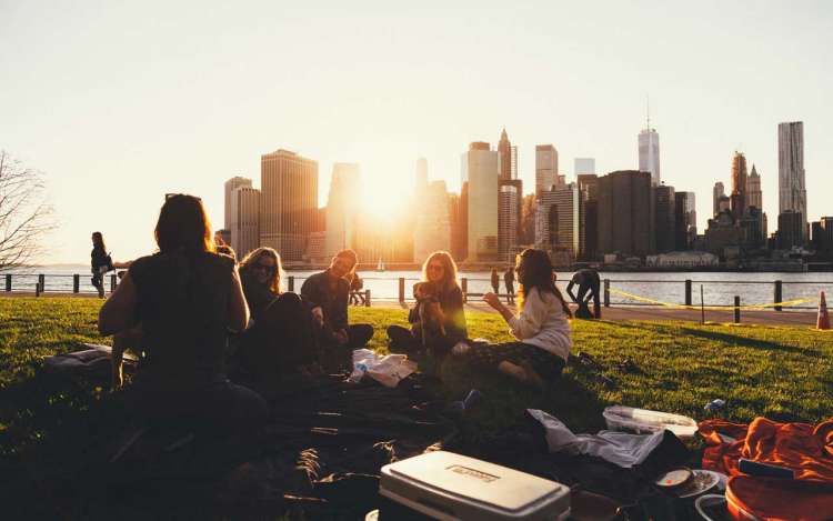 A group of friends has an outdoor picnic by the waterside. Socializing with friends has positive effects on memory.