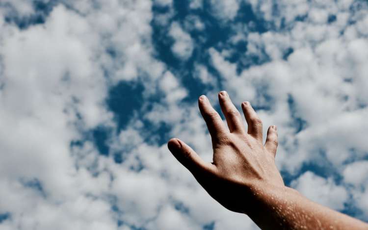 A hand reaches into a partially cloudy sky. Letting go of outcomes is a good concentration exercise.