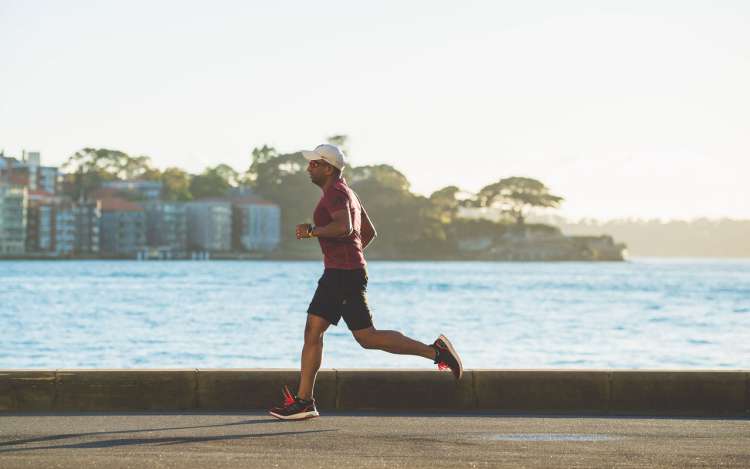 A person runs along a body of water. Keeping healthy through regular exercise is a key part of your memory strategy.