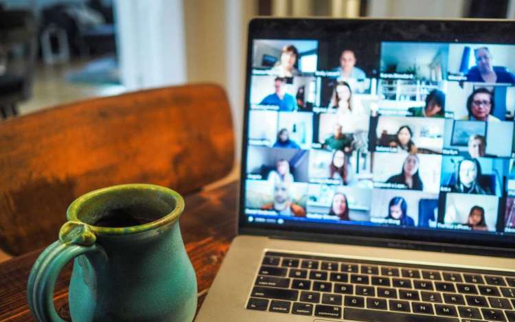 A mug of tea sits next to a laptop showing a group video conference. Study groups and accountability partners may not meet in person due to health concerns due to the pandemic.