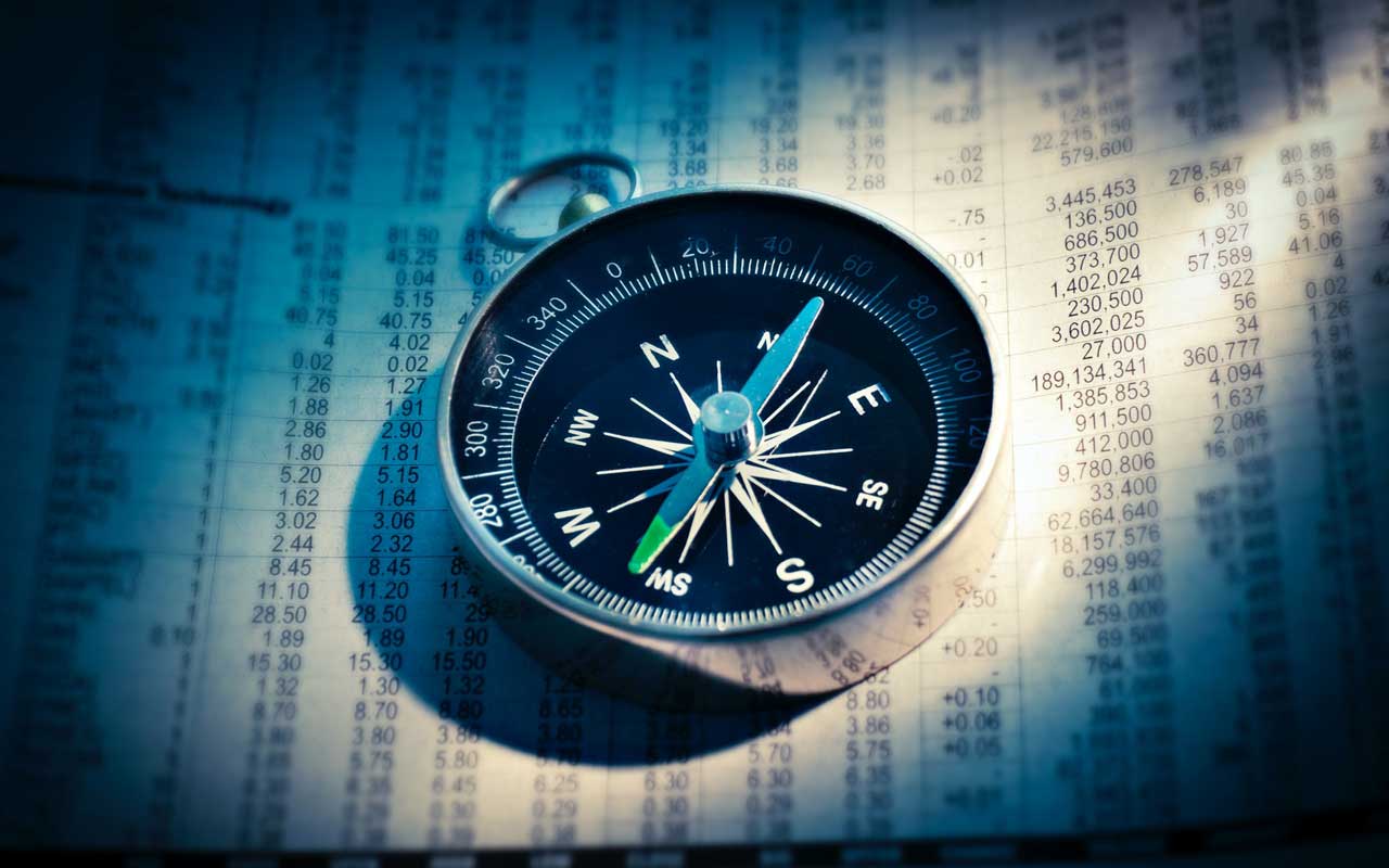 A compass sits on top of a newspaper. Much like a compass helping you determine what direction you are going, how to focus while studying can help you determine your memory journey direction.