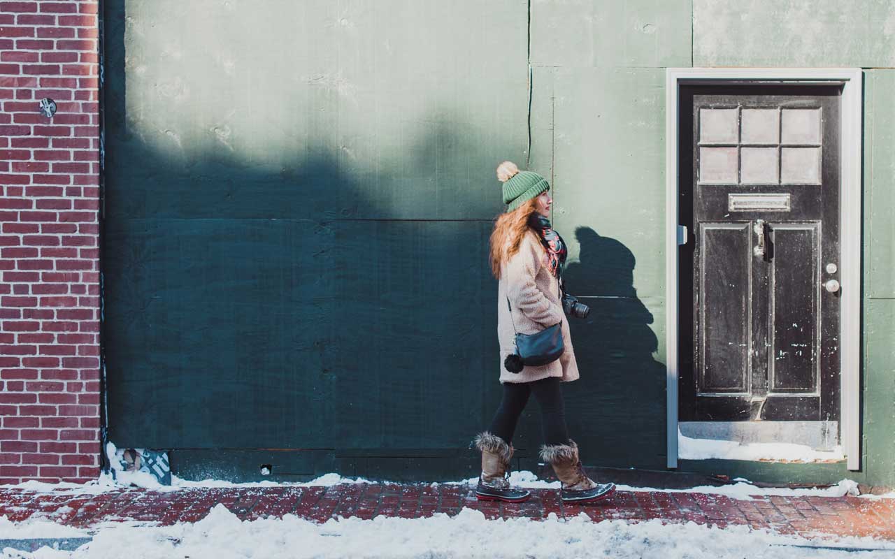 A woman walks along a snowy city street. Taking walks without technology can be a great way to concentrate.