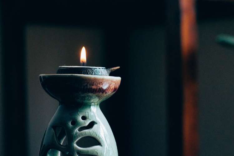 A candle burns in a pottery candle-holder. A candle can be used for the single point of focus during dharana (concentration).