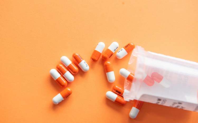 A bottle of prescription drugs against an orange background. Memory loss can be triggered by incorrect drug combinations.