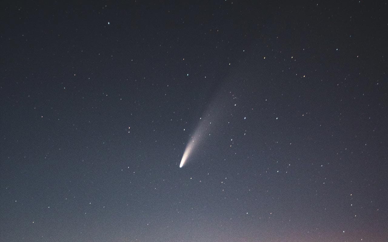 A comet streaks across a darkened sky. Using Halley