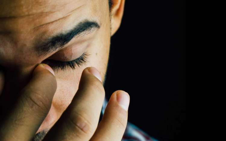 A stressed man pinches the bridge of his nose. High levels of stress are harmful to your memory.