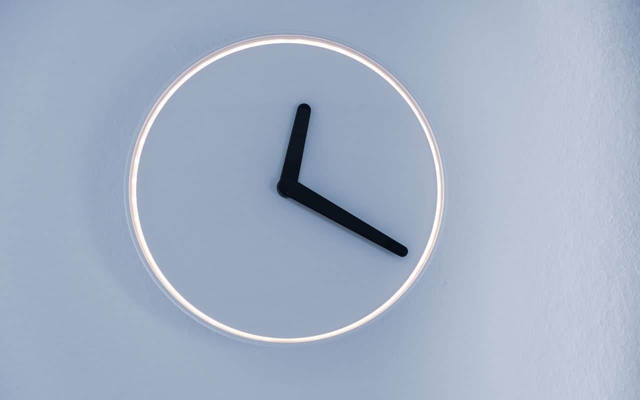 An analog clock with no numbers against a light blue wall.