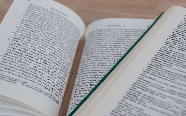 Books in two different languages lay open on a table. Becoming fluent in a language takes time.