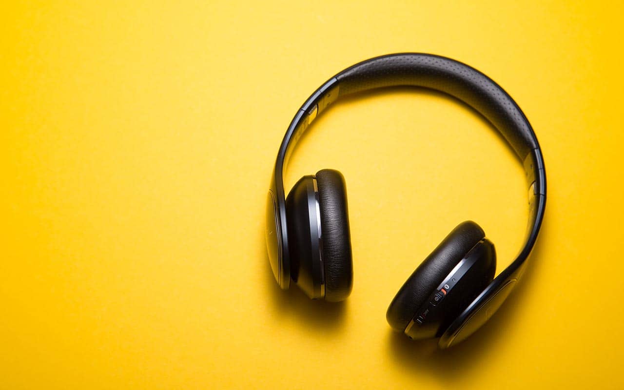 A pair of noise cancelling headphones against a bright yellow background.