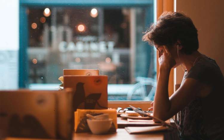 A person sits at a cafe table studying a stack of papers.