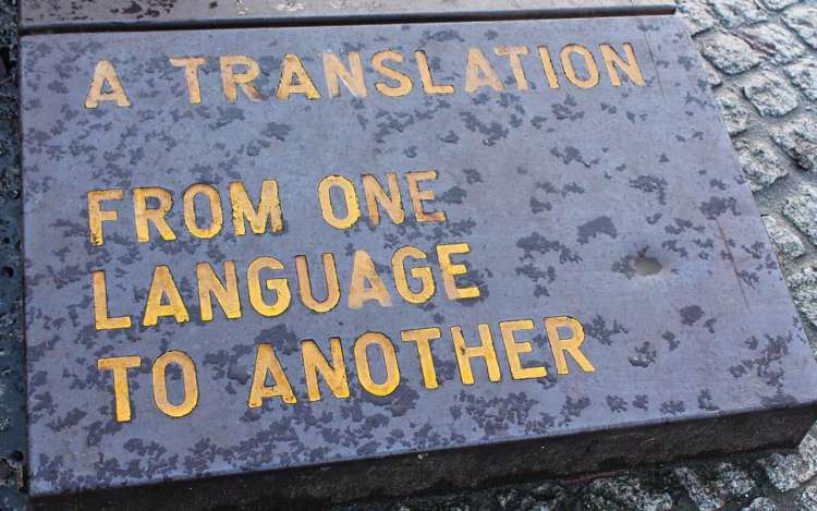 A gray stone laid in the ground with yellow text that reads, "A translation from one language to another."