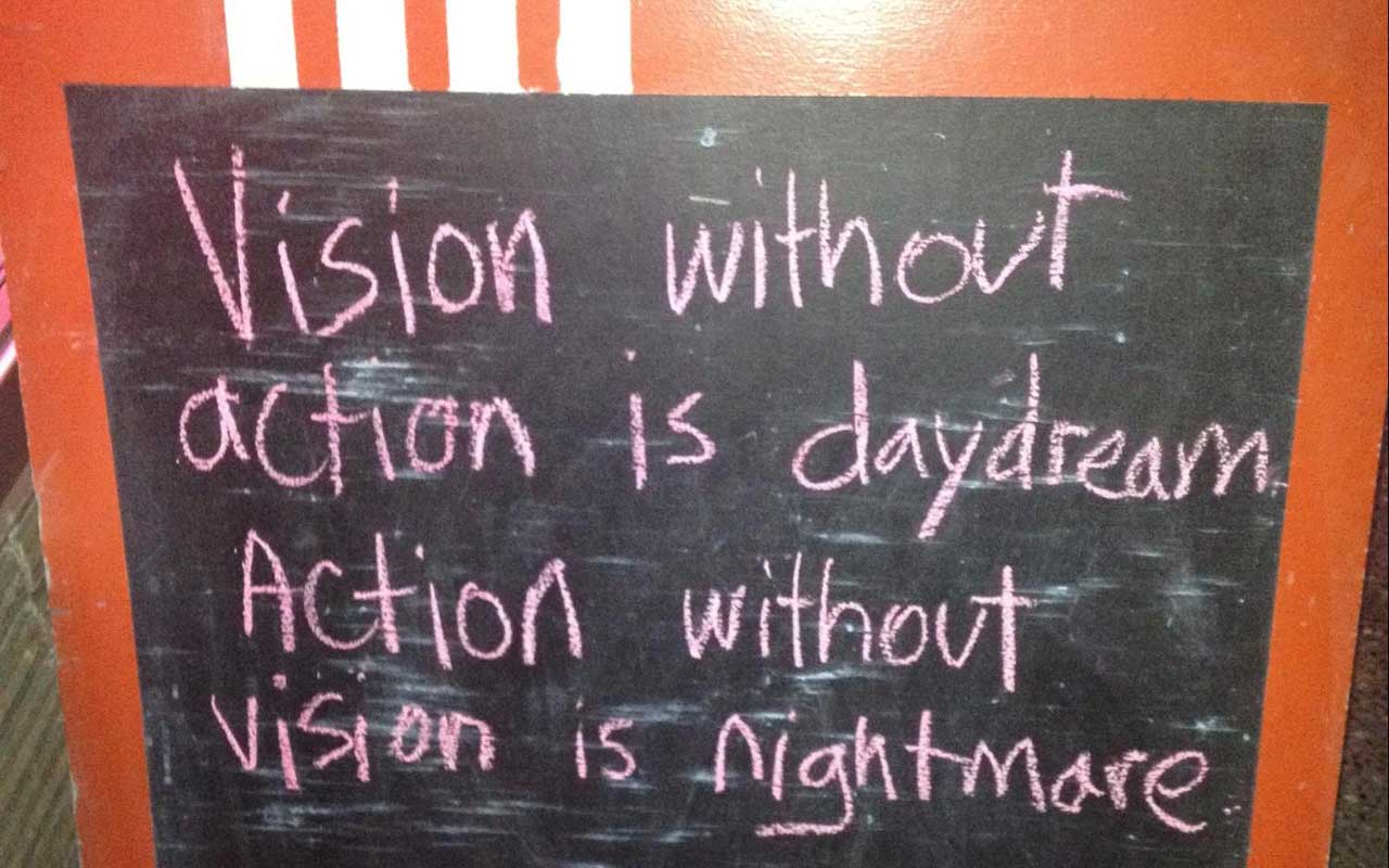 A chalkboard sign outside a cafe reads, "Vision without action is daydream. Action without vision is nightmare."