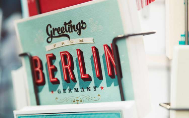 A postcard in a rack reads, "Greetings from Berlin." German is one of the top business languages.