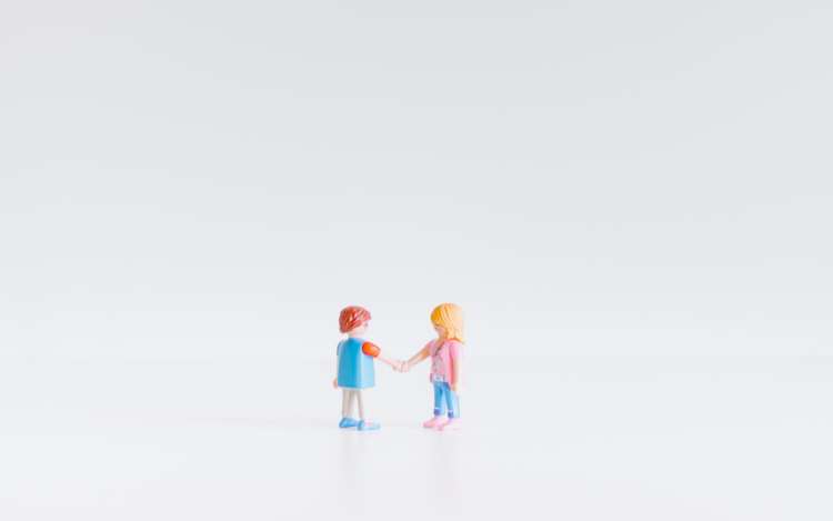 Two figurines shake hands. Use this step to assess your client base and workforce to determine your best language to learn for business.