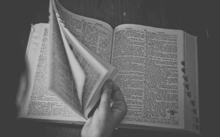 A person flips through the pages of a large dictionary. Having a large vocabulary can help you think faster.