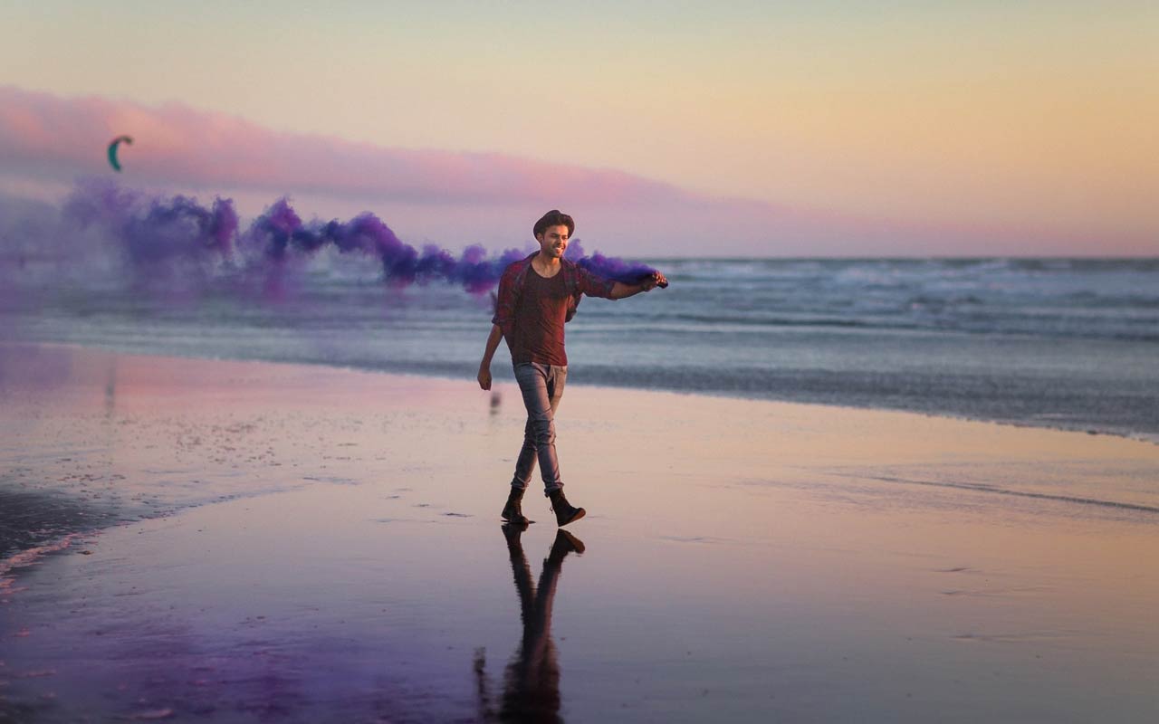 A person walks along a beach at sunset.