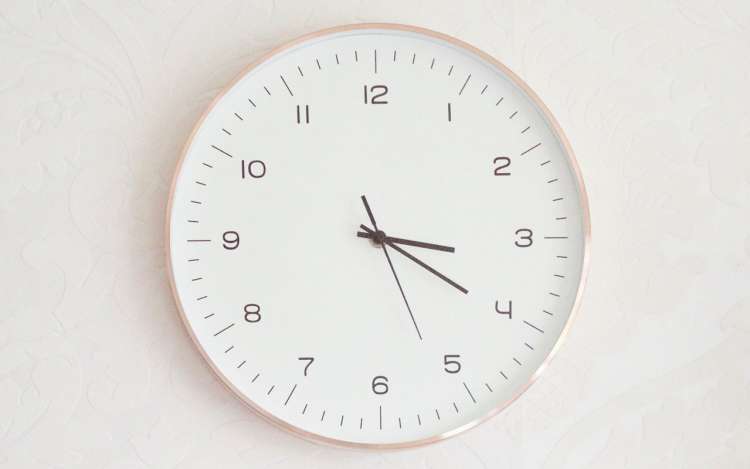 A rose and white colored clock against a white wall. Finding the best time to learn Spanish will be up to you.