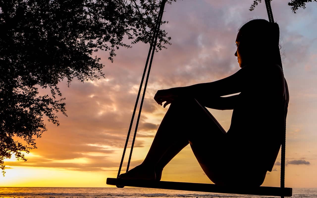 a woman on swing watching sunset