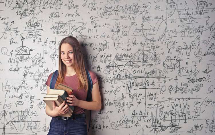 a woman holds books in front of a black board