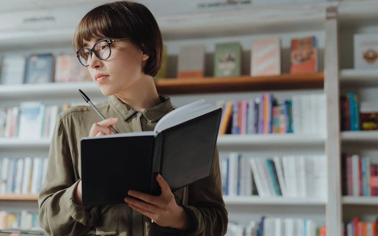 a woman is writing on a book