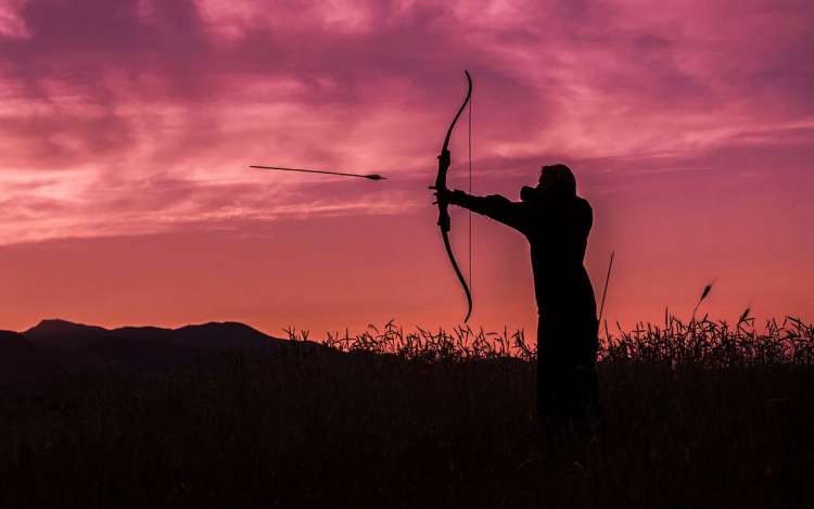 a man is shooting with a bow and arrows