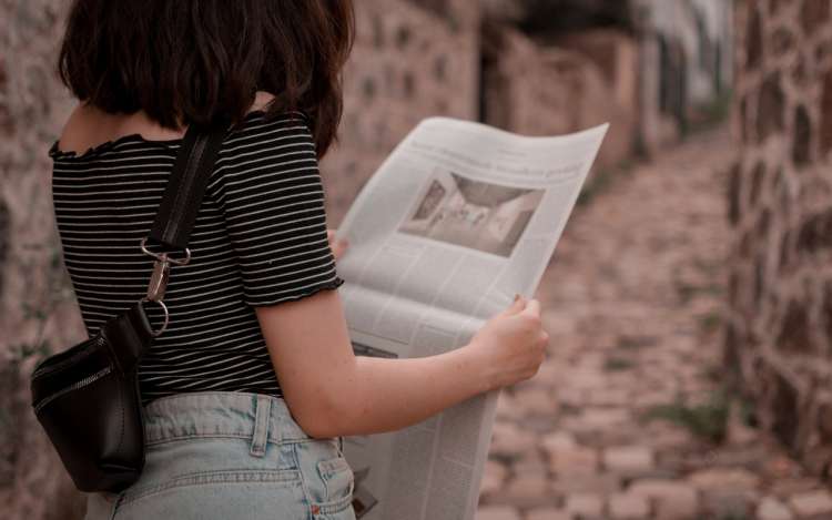 a woman is reading a newspaper