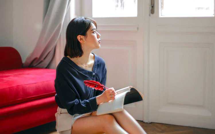 a woman is thinking and writing on the floor