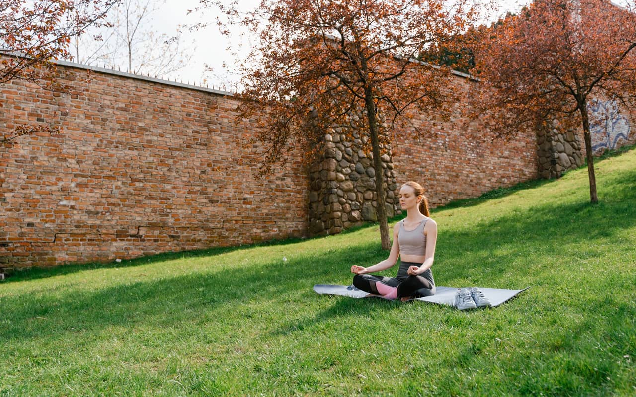 a girl is meditating in red wall park