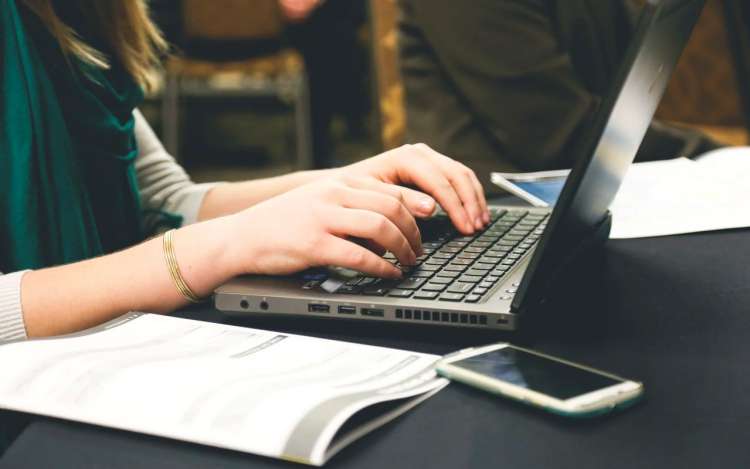 a woman is typing on her laptop