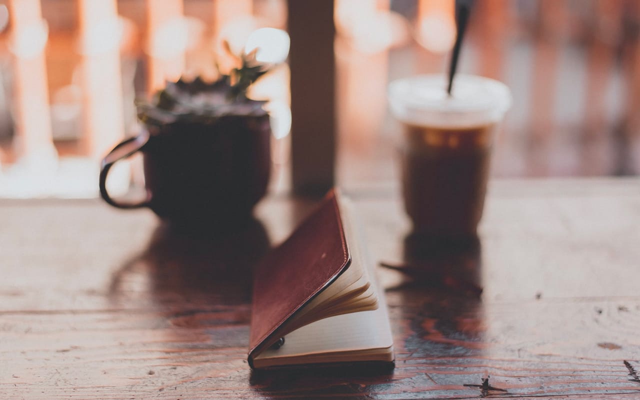 notebook coffee and plant on a desk